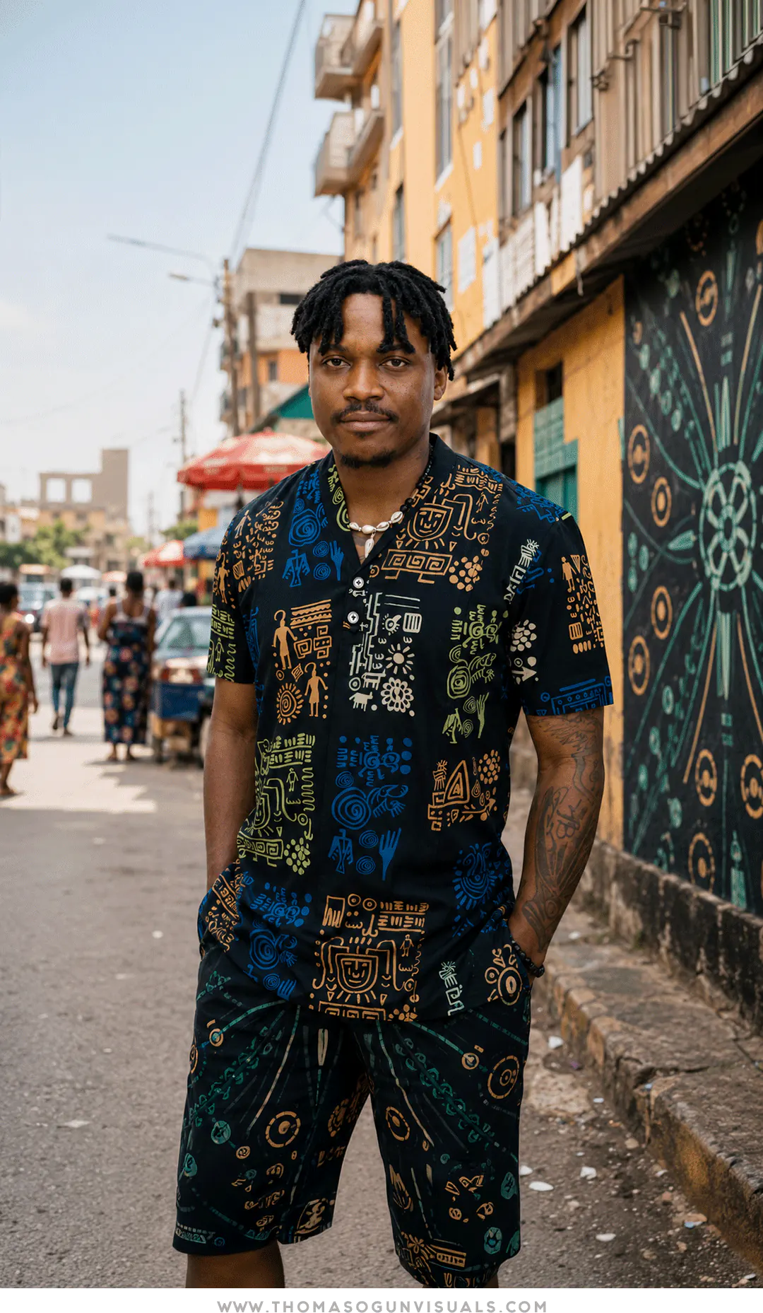 Thomas Ogun wearing clothing developed from his artwork beside a matching mural