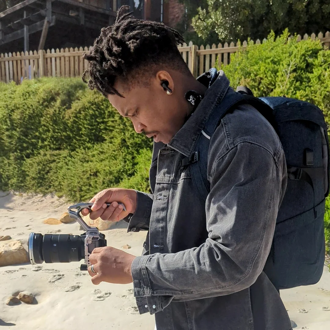 Thomas Ogun holding a camera outdoors during a creative production