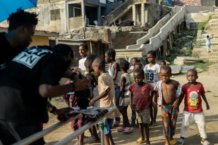 Camera team filming among children in a Nigerian neighbourhood