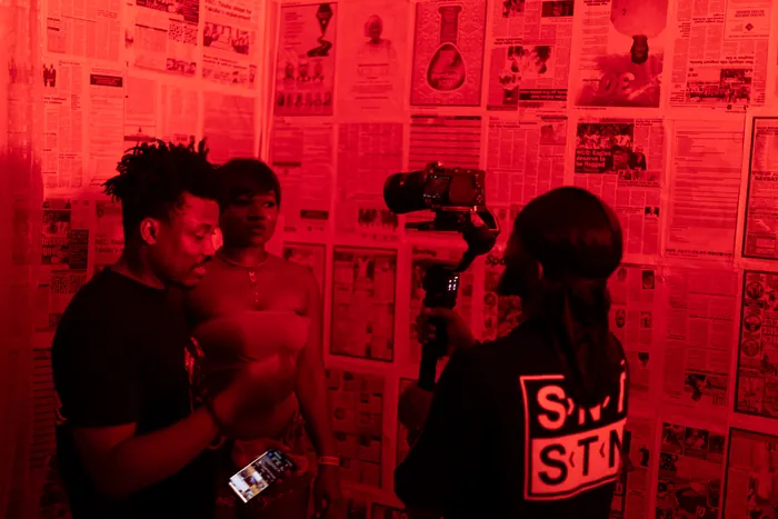 Thomas Ogun reviewing a red-lit performance setup with the camera team