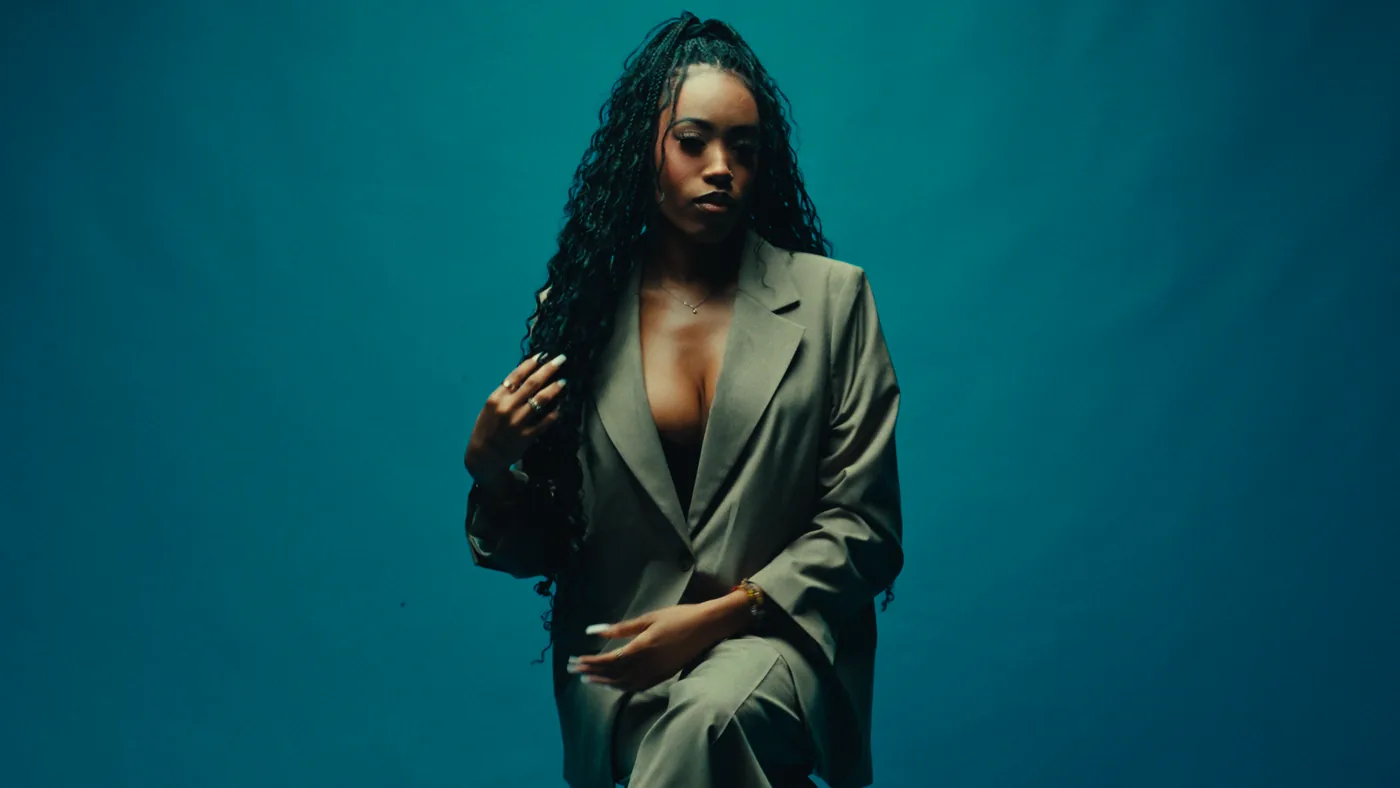 Studio portrait of a woman in a tailored suit against a teal background